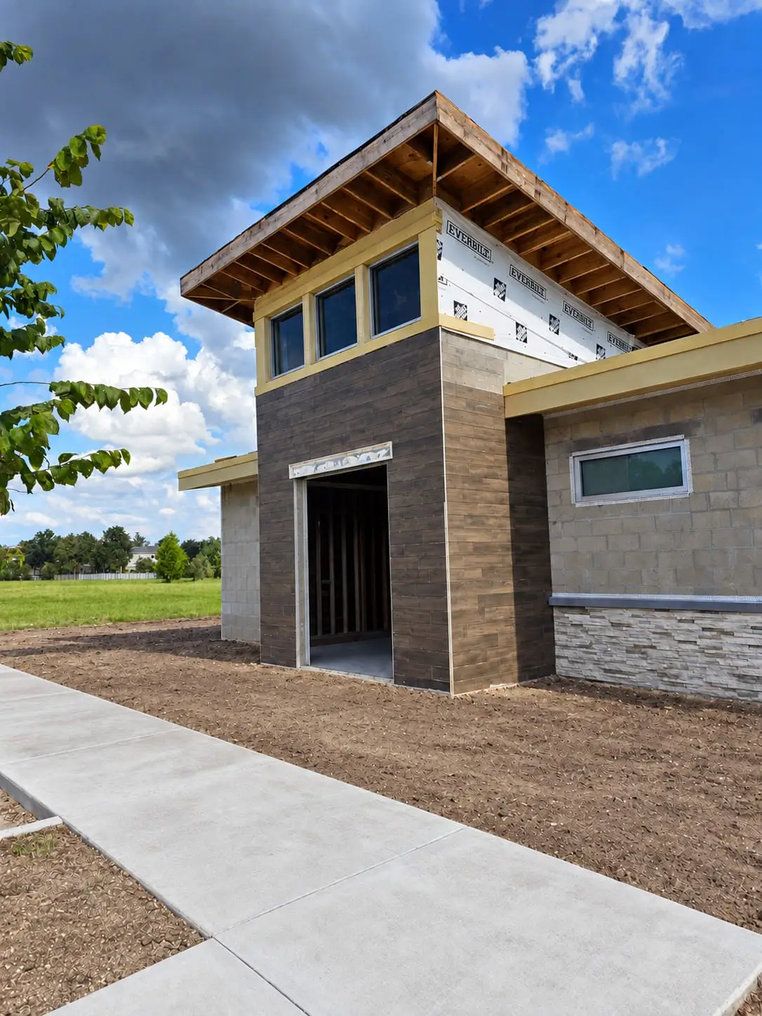 New commercial building entrance clad in dark tile panels and stacked stone at the base