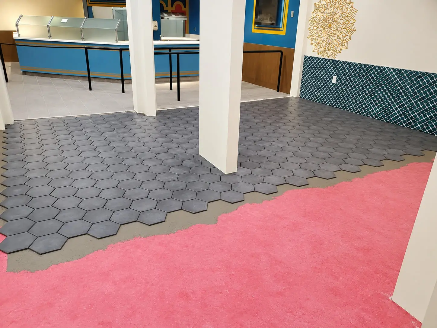 Hexagonal porcelain floor tile being laid over a waterproofing membrane in a retail space
