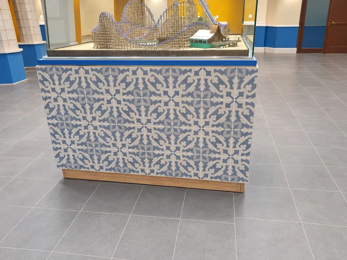 Display plinth clad in blue and white patterned tile in the middle of a large-format tiled floor