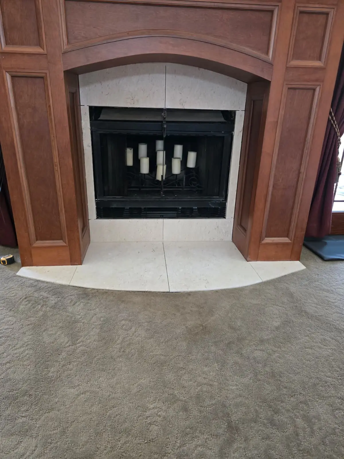 Fireplace with a light tile face and curved tile hearth set inside a carved wood surround