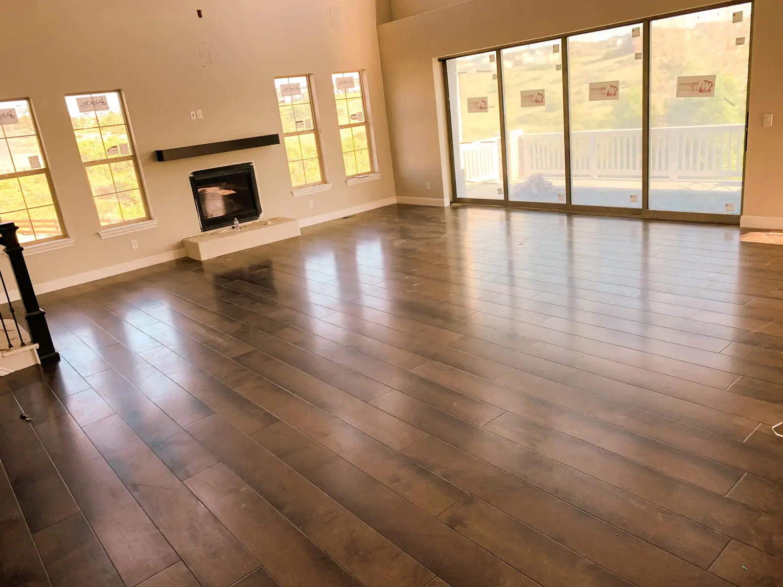 Dark wood-look plank floor running the length of a living room, past a fireplace and out to a wall of windows