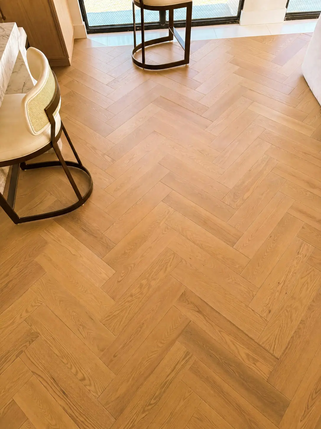 Oak herringbone floor running through a dining area, the points aligned along a single axis