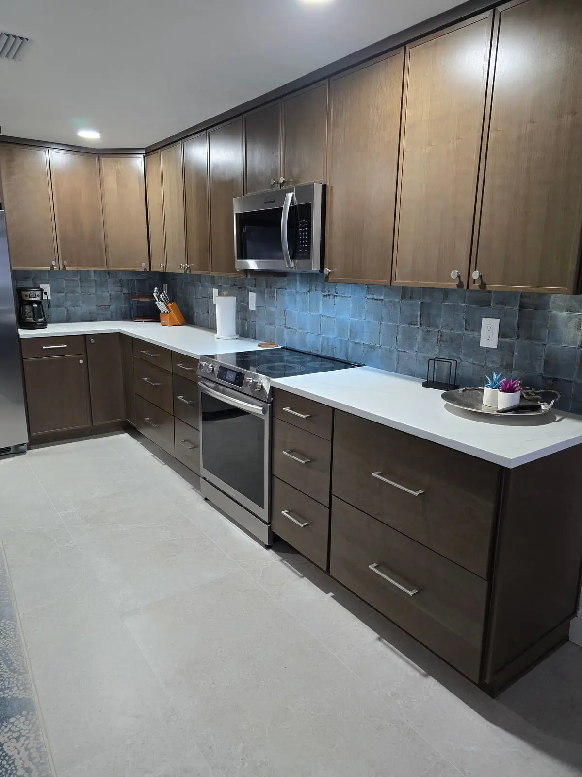 Kitchen with dark wood cabinets and a blue-grey tile backsplash run the length of the wall