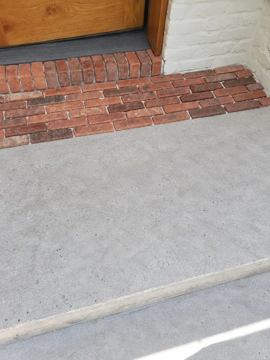 Brick threshold laid at a doorway where it meets a poured concrete apron