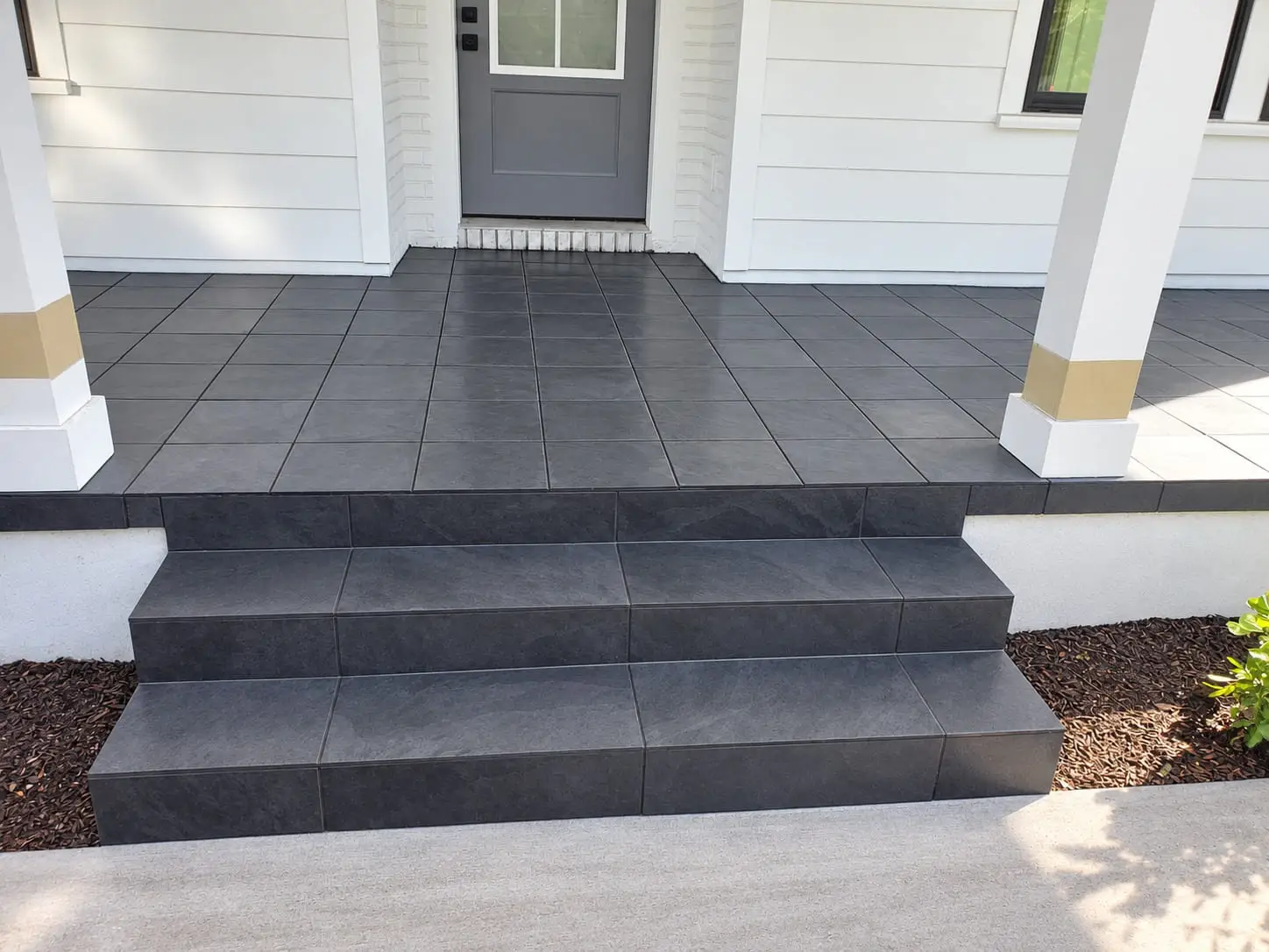 Entry steps and landing in dark porcelain with a bullnosed edge on every tread, leading up to a side door