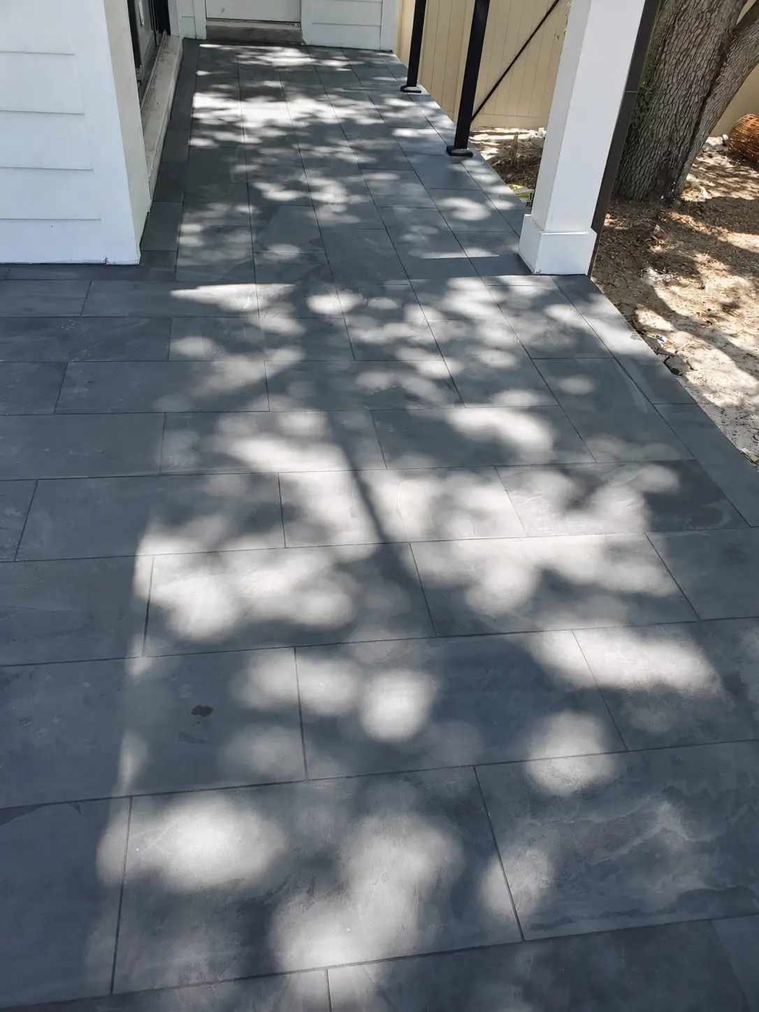 Paver walkway running down the side of a house, laid to fall away from the wall