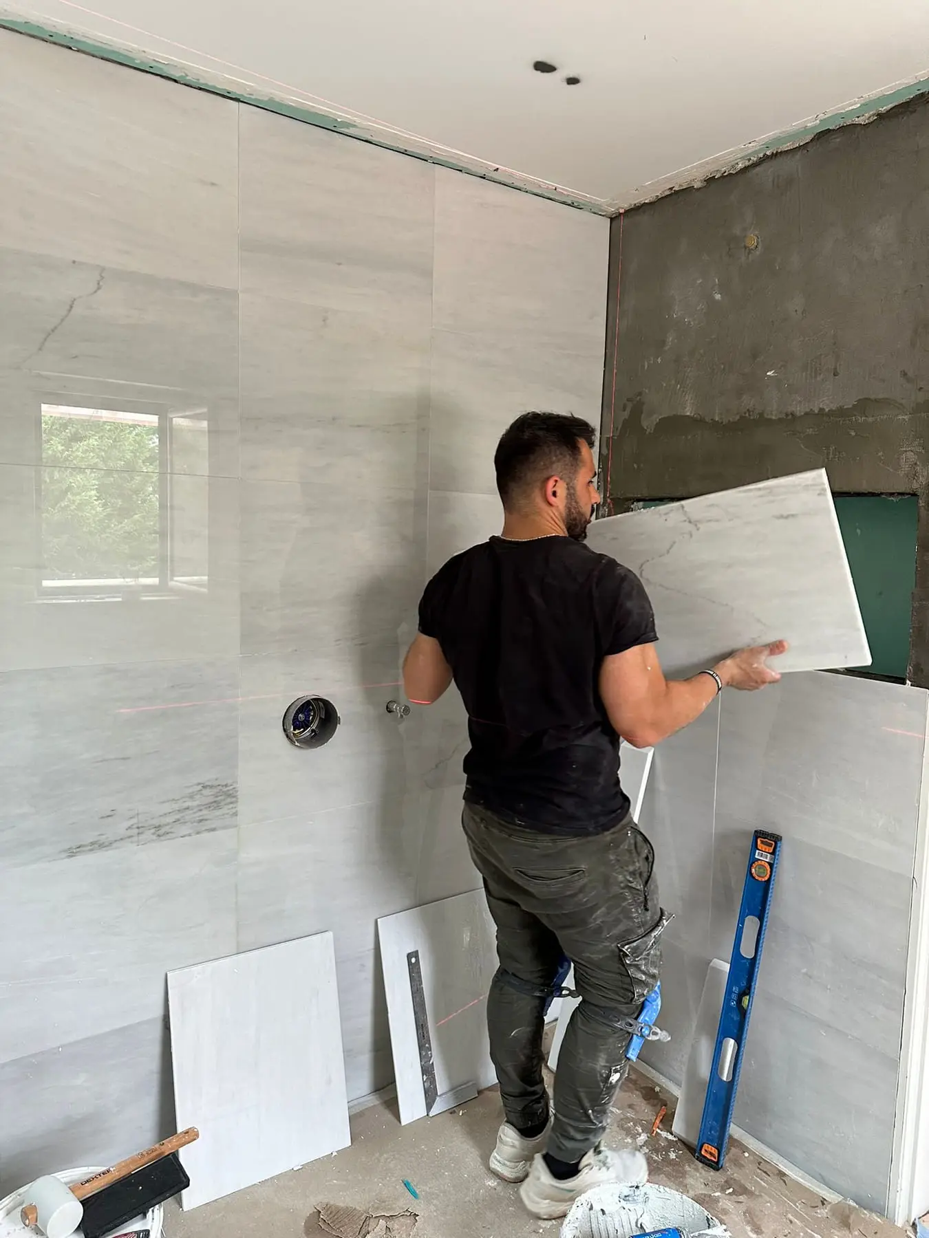 Installer setting a large-format wall panel by hand on the Portugal project
