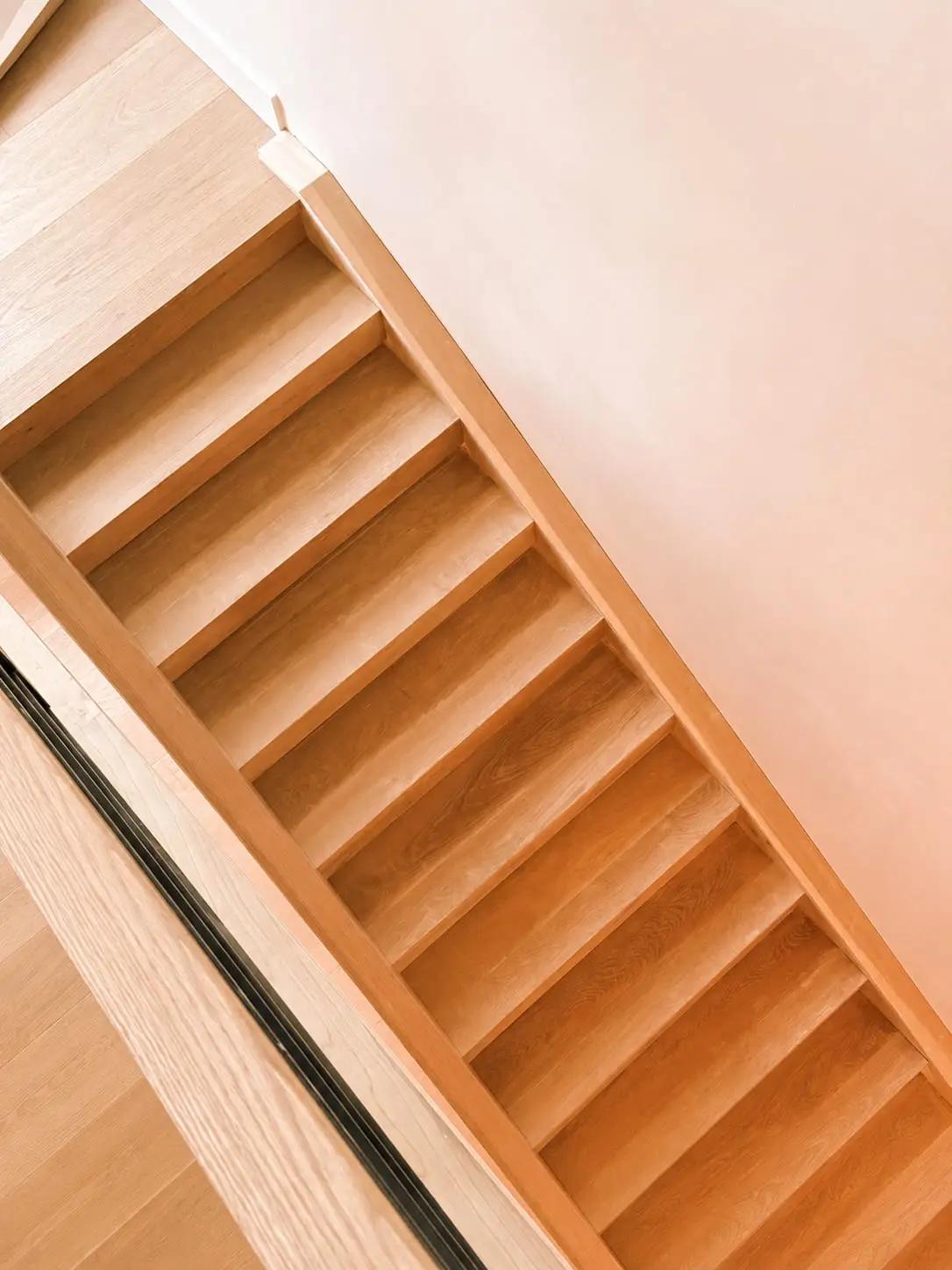 Oak stair flight seen from the landing above, the treads and the landing floor running in the same oak
