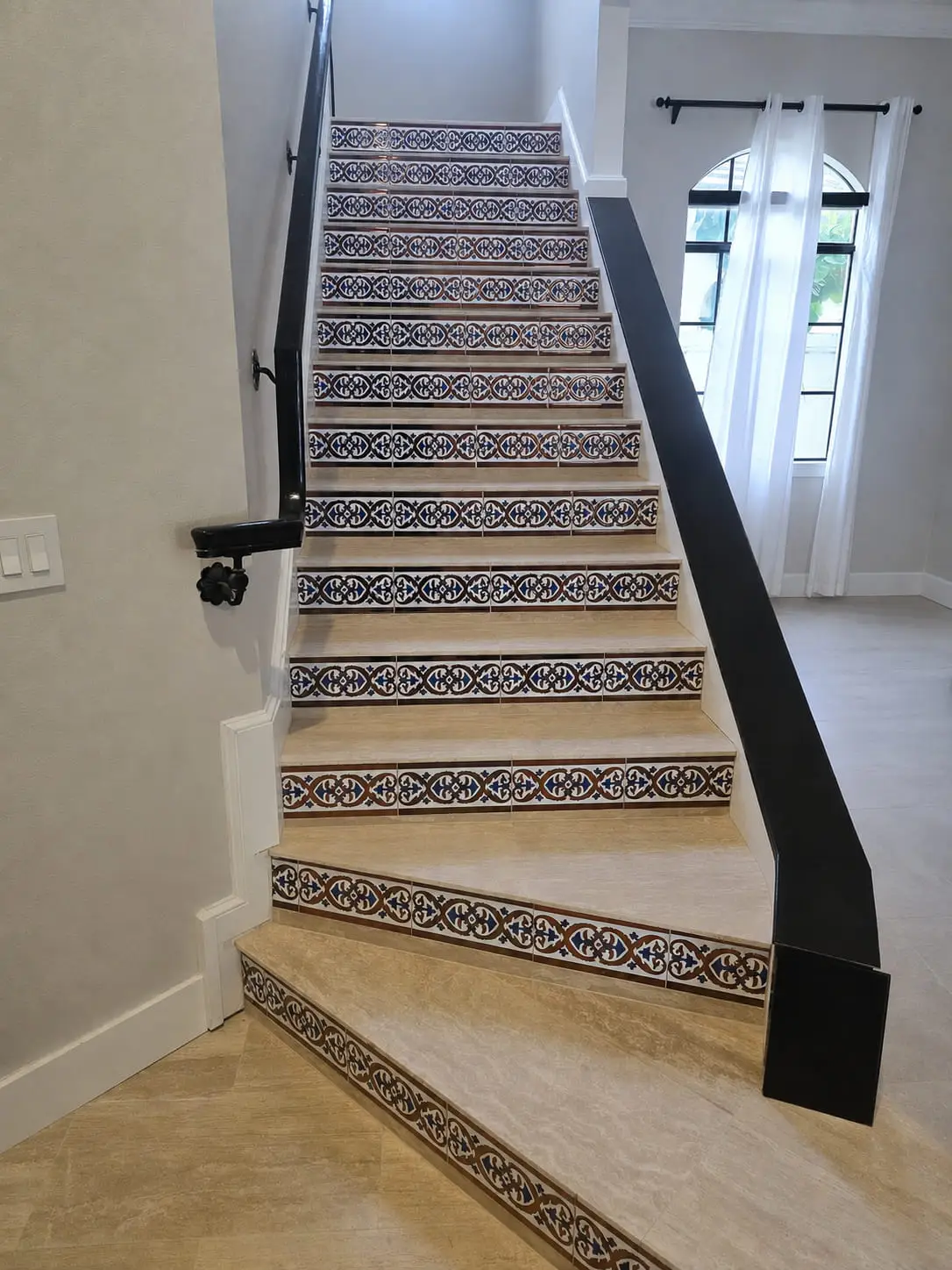 Stair with patterned encaustic-look tile risers and a runner of the same tile carried across the hall floor